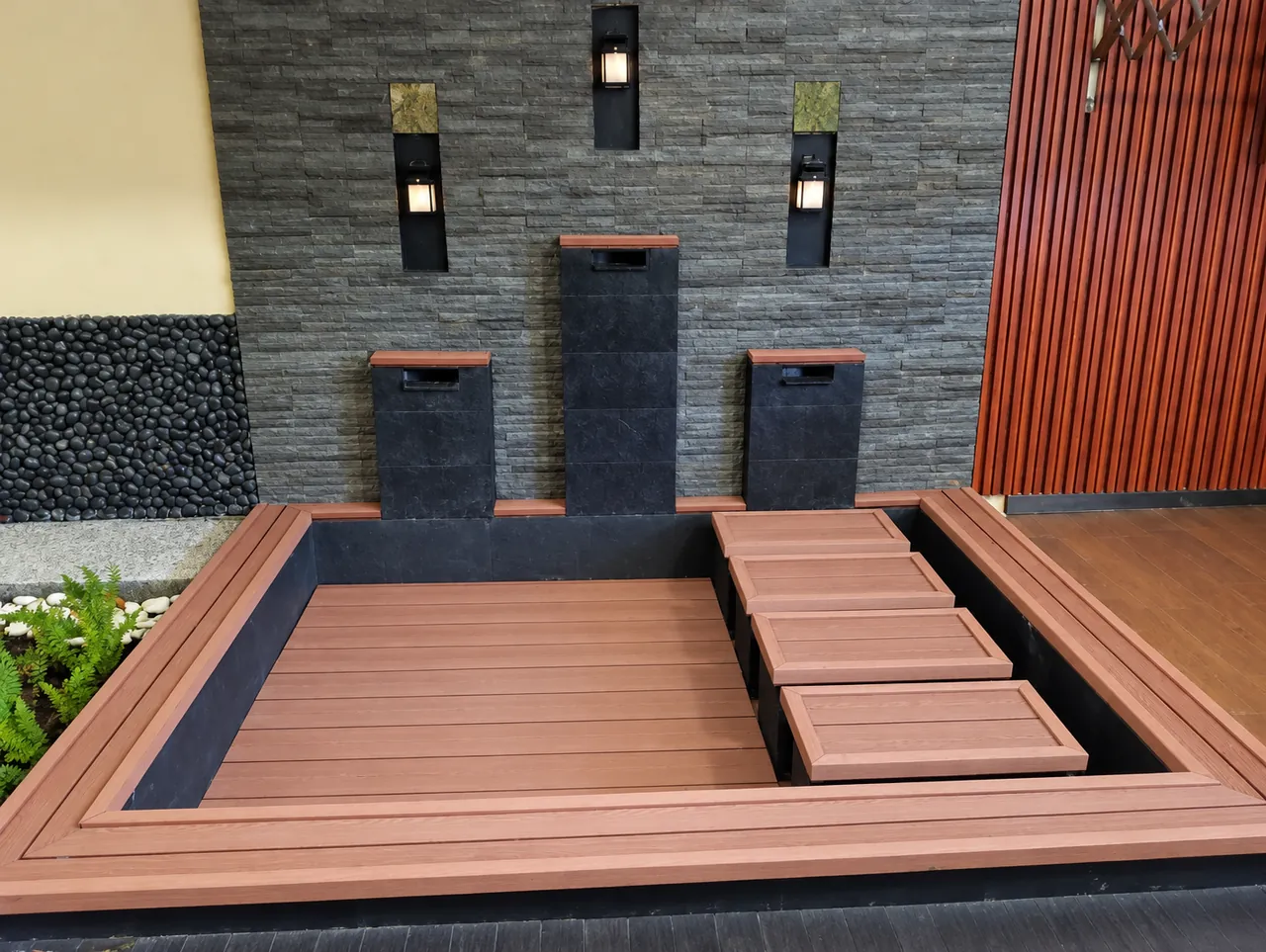 Decking WPC Champion dengan undakan di samping dinding batu